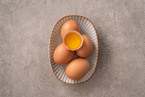 Top view of fresh brown chicken eggs in a plate on gray table background.