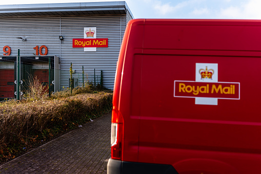 Plymouth, Devon, UK - Dec 19th 2021: Royal Mail, Mail Centre (depot), Red transit postal van parked outside loading bay. Two logos in shot.