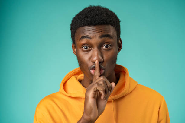 istock Black man showing silence gesture with finger on his lips 1388173071