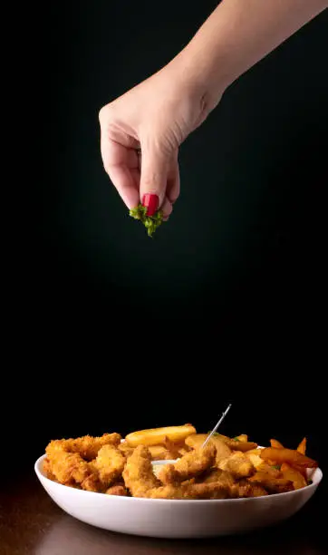 food-styling - cheff woman spreading green onions in fish and chips portion