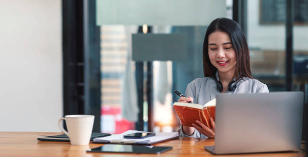 istock Confident businesswoman writing down note and working on laptop at her workplace at modern office. 1388177685