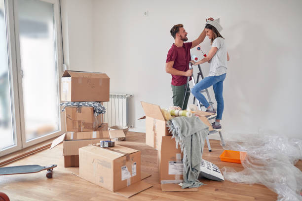 istock cute couple having fun while preparing to paint white wall in new apartment, standing on a ladder, holding paintbrushes, smiling, laughing 1388178249