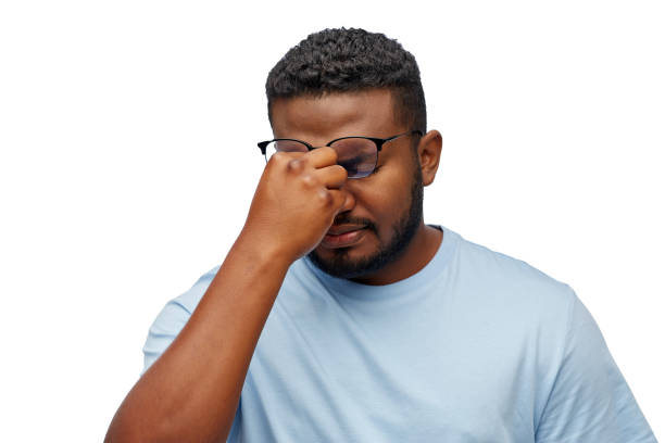 tired african man in lasses touching nose bridge stock photo