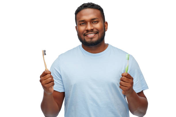 istock african man with wooden and plastic toothbrushes 1388185007