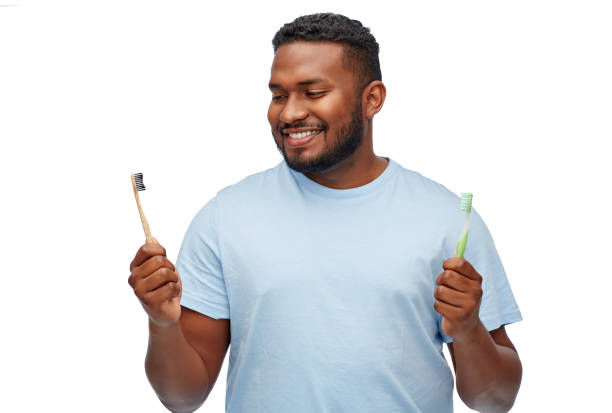 african man with wooden and plastic toothbrushes