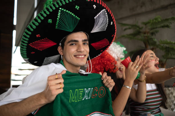 portrait of a teenage latin boy watching the mexico soccer team playing at home with friends - mexico team voetbal 個照片及圖片檔