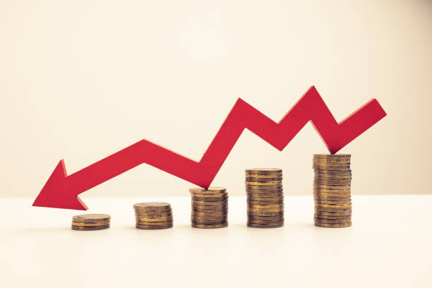 istock Red down arrow. Stack of gold coins, steps down. Money loss concept. 1388188759