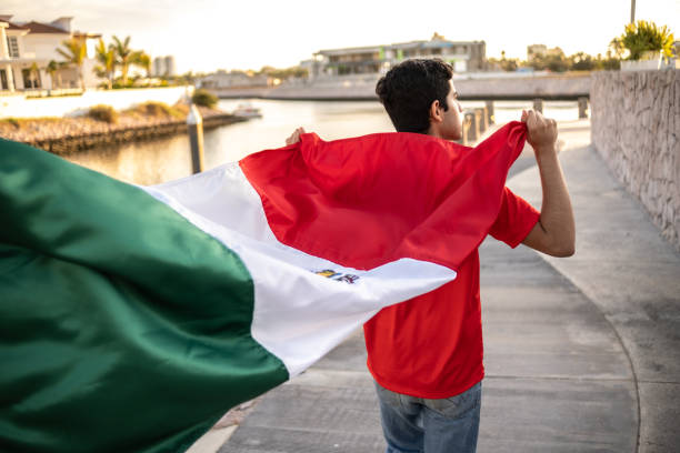 Teenage Latin boy holding the Mexican flag outdoors Teenage Latin boy holding the Mexican flag outdoors international soccer event photos stock pictures, royalty-free photos & images