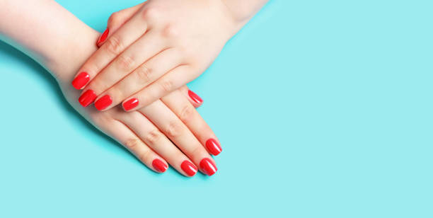 istock Female hands with red manicure on blue background, copy space. 1388189909