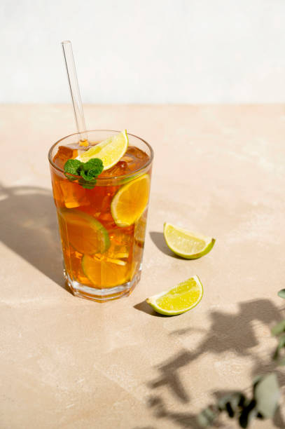 iced tea with lemon, fresh mint leaves and ice in tall glasses with sun light and shadows. - chá gelado imagens e fotografias de stock