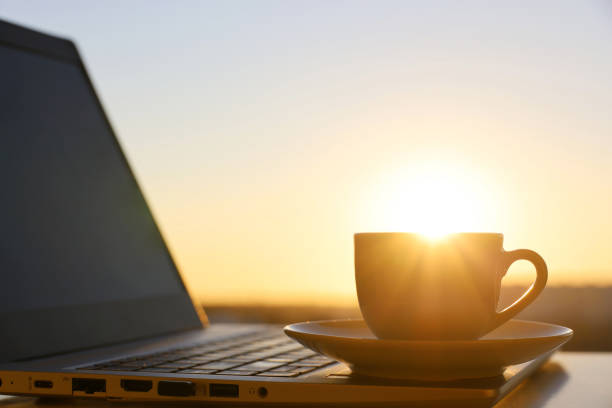 istock Coffee or tea cup on laptop against the window with sunshine 1388192760