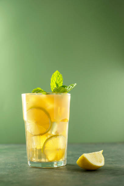 Lemonade with fresh mint and ice cubes in glass. Refreshing summer drink. Green background. Lemonade with fresh mint and ice cubes in glass. Refreshing summer drink. Green background Lemon Juice stock pictures, royalty-free photos & images