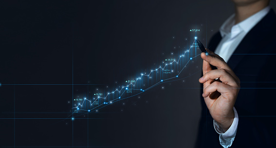 Businessman draws growing virtual hologram of statistics, graph and chart. Stock market and analyzing sales data.Investment of growth on currency rate. Finance trade and stock concept