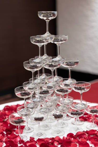perle di tapioca in champagne vetro piramide torre decorata con petali di rosa su tavolo di stoffa bianca - luxury milk dinner glass foto e immagini stock