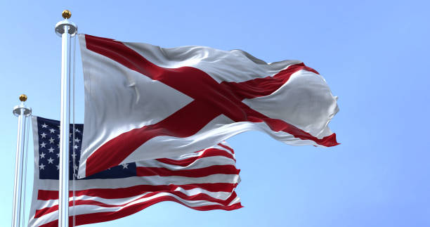 The flags of the Alabama state and United States of America waving in the wind. stock photo