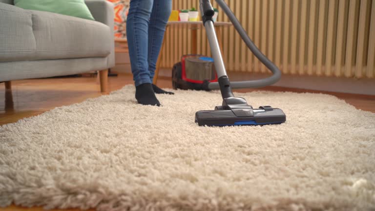 Young woman vacuuming the living room at home