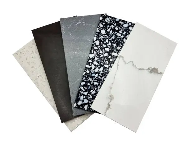 Photo of different quartz samples swatch for kitchen counter top with precise processed edges isolated on background with clipping path. multi color and pattern of artificial stones (focused at black pebble).