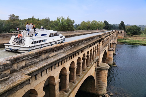 Boat across river Orb bridge on historic Canal du Midi in France. Canal du Midi is a UNESCO World Heritage Site.
