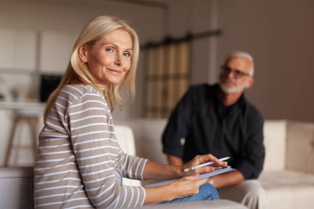 donna psicologa sorridente a una sessione di psicoterapia. aiutare un uomo maturo con depressione e burnout. - mental health professional senior adult social services mental health foto e immagini stock