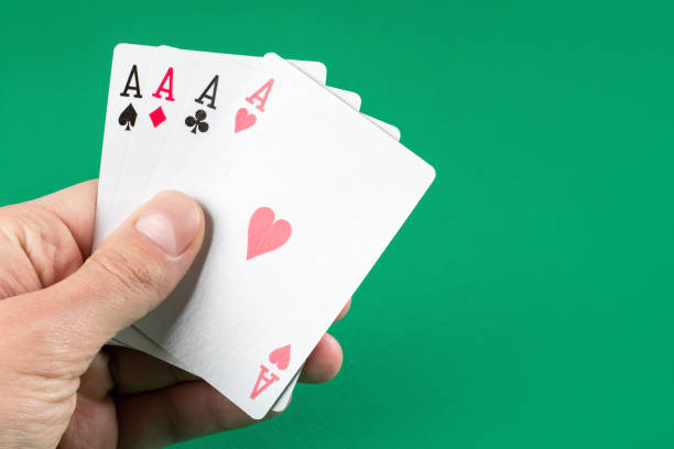 istock Playing cards in hand on green background 1388203863