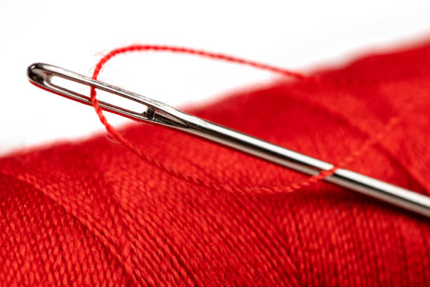 Skein with black thread in needle's eye on white background