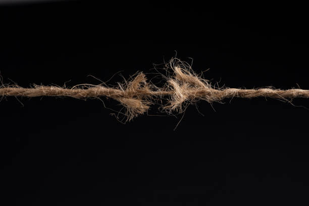 istock Frayed rope ready to break isolated on black background 1388204269