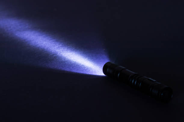 istock Flashlight and a beam of light in darkness. A modern led lamp with bright projection on dark table. Surface with copy space 1388205412