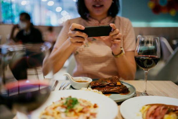 asian woman taking photo of her meal with smartphone before eating it in restaurant - gourmet enjoyment food freshness imagens e fotografias de stock
