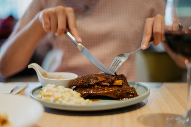 istock Young woman eating pork ribs in restaurant 1388207632