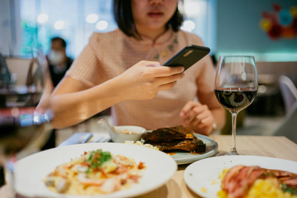 asian woman taking photo of her meal with smartphone before eating it in restaurant - gourmet enjoyment food freshness imagens e fotografias de stock