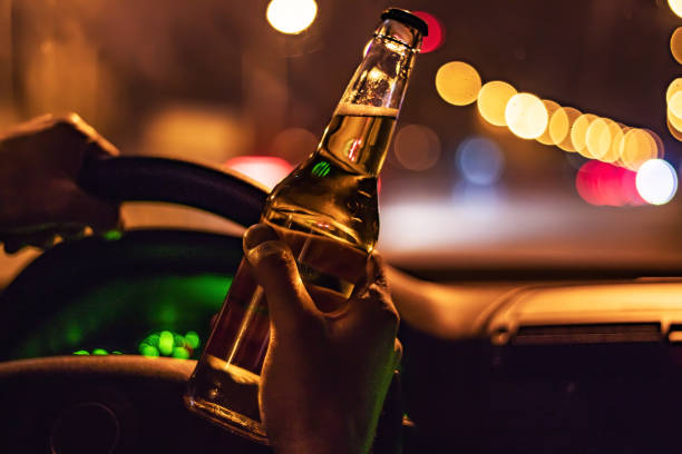 istock Man drink beer while driving at night in the city. Dangerously driving 1388208757