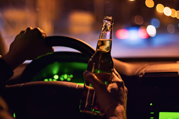 istock Man drink beer while driving at night in the city. Dangerously driving 1388208764