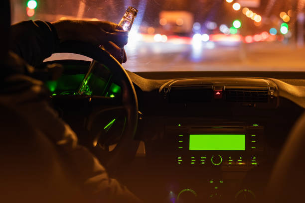 istock Man drink beer while driving at night in the city. Dangerously driving 1388208771