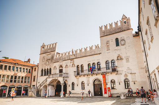 Koper, Slovenia - August 8 2020: The Praetorian Palace, Gothic palace in the city of Koper with people, mostly tourists, walking around