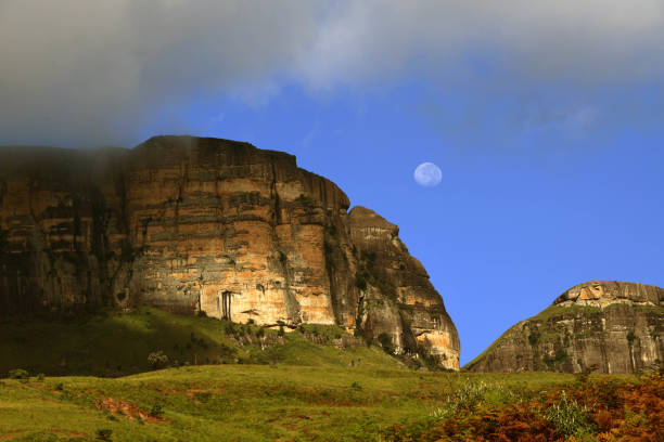 The moon seen over the rock face of a Drankensberg mountain