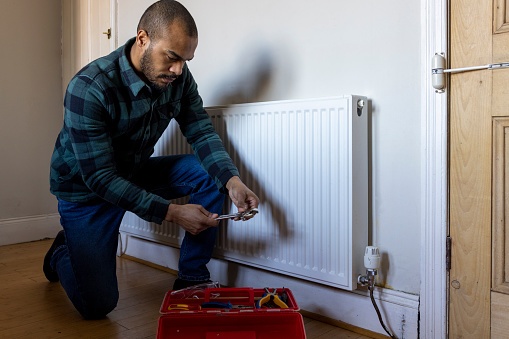 Man maintaining a radiator at a home in the North East of England in order to conserve energy.