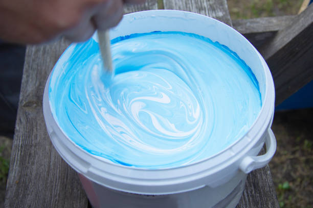 blue and white paint were mixed in a bucket. stir with a stick