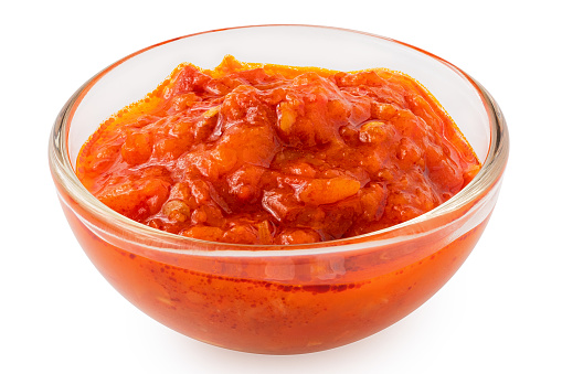 Ajvar in a glass bowl isolated on white.