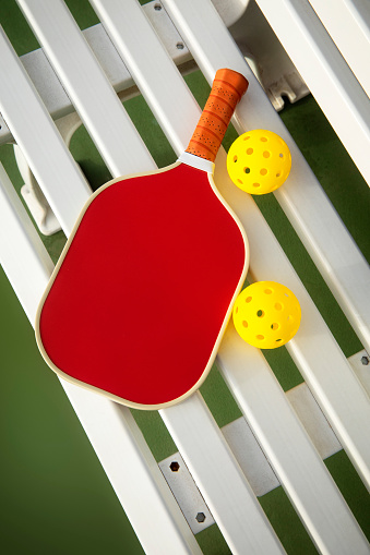 This is a photograph taken in the studio of a pickleball paddle and balls on a outdoor court