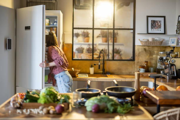Woman looks into a fridge while cooking in the kitchen at home
