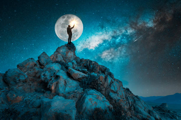 istock man standing on the rock outdoors under the starry night and full Moon 1388225694