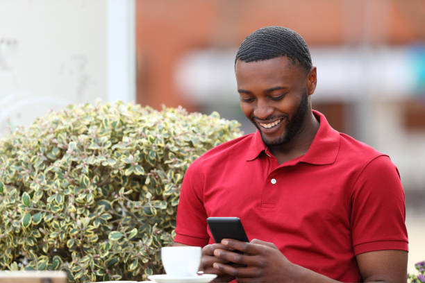 istock Happy man with black skin using phone in a bar 1388226277