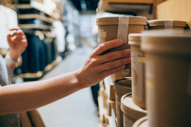 un primer plano de una mujer caucásica anónima en una tienda que sostiene un paquete biodegradable de algún producto que decide si comprarlo o no - embalaje fotografías e imágenes de stock