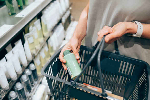 An Unrecognizable Caucasian Woman Buying Some Cosmetic Products An anonymous female customer holding her basket while shopping on Black Friday. makeup product photography stock pictures, royalty-free photos & images