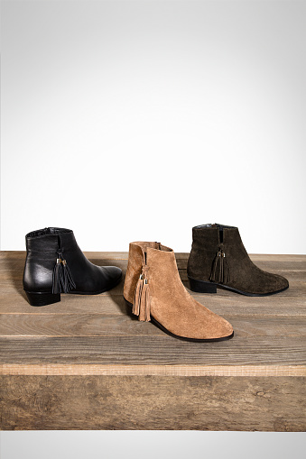 Suede ankle boots isolated on wood table (with clipping path)