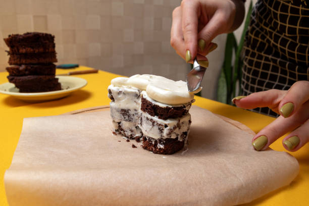 istock With palette knife, women's hands level the cream on the bento cake biscuits. The process of making dessert at home. Selective focus. 1388227510