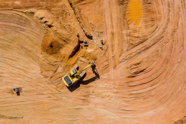 istock Excavator working backhoe digs ground of preparation process for new residential complex buildings with construction of storm water pits sanitary 1388227619