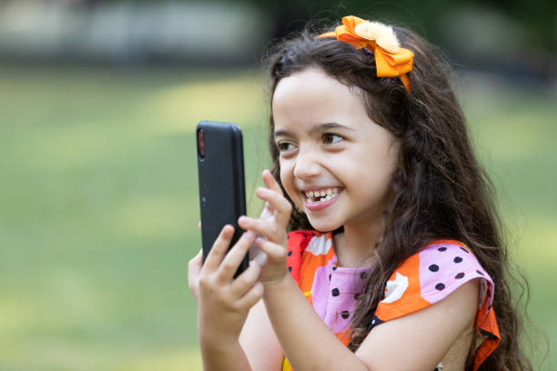 istock Little girl smiling using smartphone. Taking pictures. 1388227723