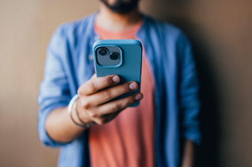 An anonymous handsome Indian male using his new smartphone to take a selfie.