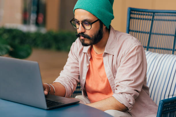 istock A Happy Casually Dressed Man With Moustaches Sitting Outdoors At Computer And Chatting 1388227940